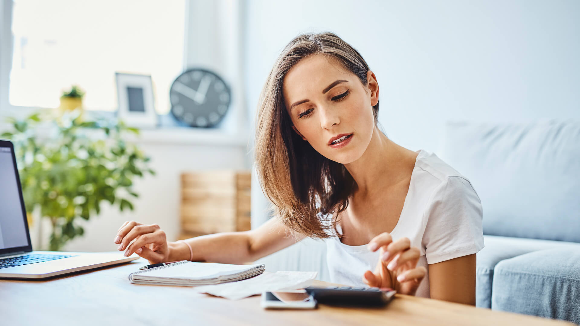 A woman sitting at the table with her hands on her cell phone.